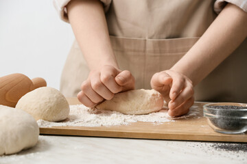 Female chef preparing dough on kitchen table, closeup