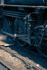 Steam train locomotive engine wheels close-up with steam coming out.  With colour toning