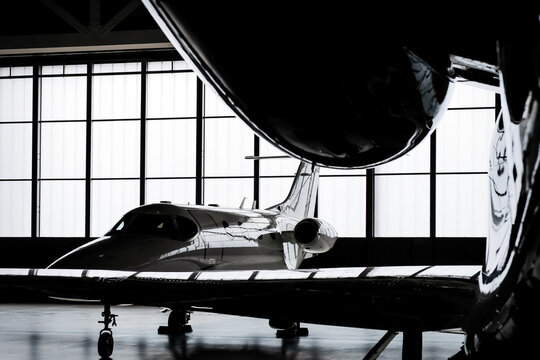 Luxury private jet plane storage inside the hangar. Natural black and white high contrast. 