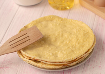 selective focus. fresh homemade cake layers lie on a plate on a wooden table. Wooden spoon. Cake on a frying pan. Fried. round sponge cake or chiffon cake on white plate 
