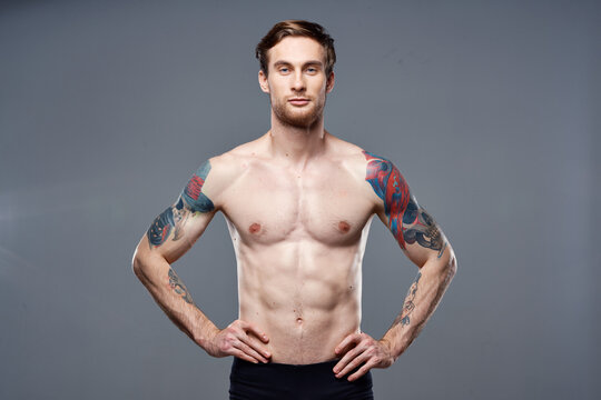 athletic man with pumped up abs tattoos on his arms