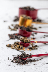 Set of different dry tea in measuring spoons on light background
