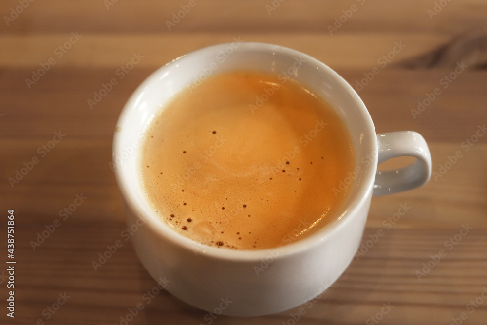 Wall mural cappuccino cup on wooden table closeup