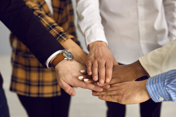 Group of people putting hands together. Diverse aspiring business team stacking hands in corporate...