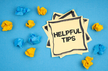 On a blue background, there are pieces of paper and a sticker with the inscription - HELPFUL TIPS