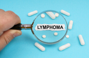 A man looks through a magnifying glass at pills and a leaf with the inscription - LYMPHOMA