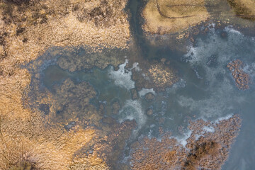 Flooded meadow with water standing in grass from directly above in wetland area. Drone view of a marsh in spring. Aerial perspective of a swamp.
