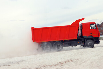 Truck moving fast on a dusty industrial road