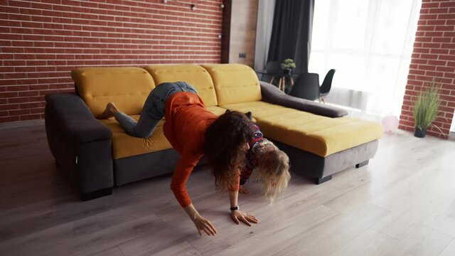 Little girl playing at home with mother and climbing on her piggyback
