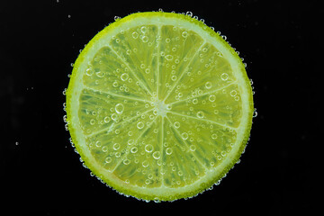 Fototapeta na wymiar Slice of lime in sparkling water on black background. Citrus soda
