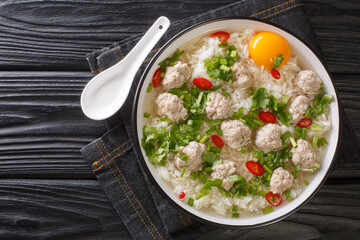 Asian food Thai Rice Soup with Pork meatballs Khao Tom Moo closeup in the plate on the table. Horizontal top view from above