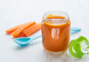 Baby carrot mashed with spoon in glass jar