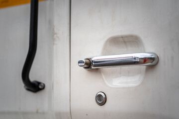 Close-up at old style metal door handle of the heavy truck or trailer vehicle. Transportation or logistic industrial equipment part object photo.