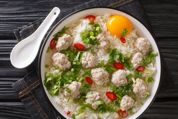 Diet rice soup with meatballs, lots of greens and an egg close-up in a bowl on the table. horizontal top view from above