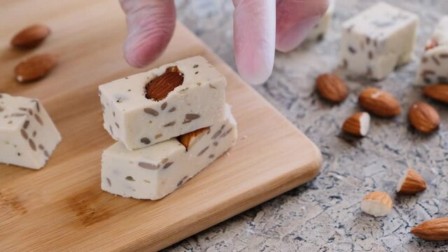 Pieces of nut halva with almonds and sunflower seeds are laid out on a wooden board. Traditional oriental dessert. Close-up.