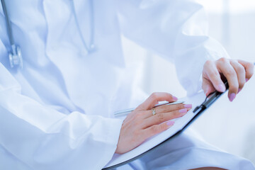 Close-up view of female doctor hands filling patient registration form. Healthcare and medical concept