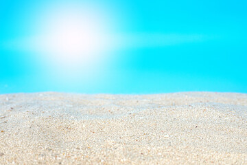 Fototapeta na wymiar Sea beach sand texture on blue background with selective focus. Summer background concept for products display. 