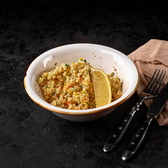 Bulgur with vegetables on black plate on Dark grey black slate background