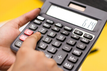 Closeup of using calculator on white textured background stock image.