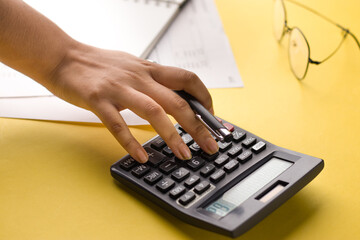 Closeup of using calculator on yellow background stock image.