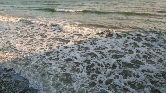 4k video top view of a wave near a pebble beach