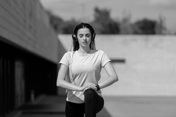 Woman listening music in city street. Sport activities on street and music. Black and white filter