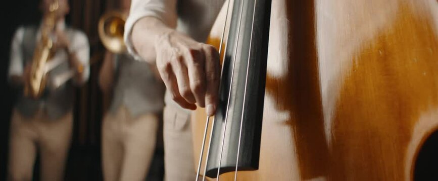 CU Caucasian male playing double bass during jazz band rehearsal or concert. Shot with 2x anamorphic lens