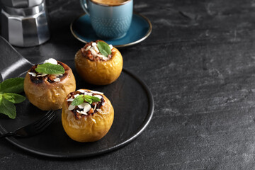 Delicious baked apples with nuts and mint served on black table, space for text