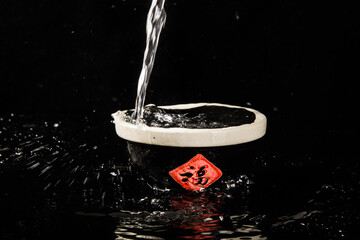 chinese liquor is poured into a ceramic bowl on black background