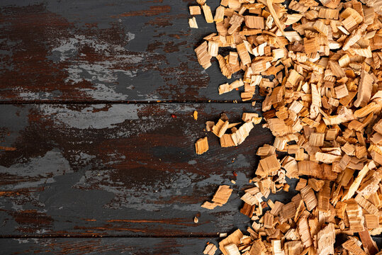 Frame from wood chips for smoking on a dark wood background top view. Copy space for text. Wood chips for smoking fish or meat, flat lay.