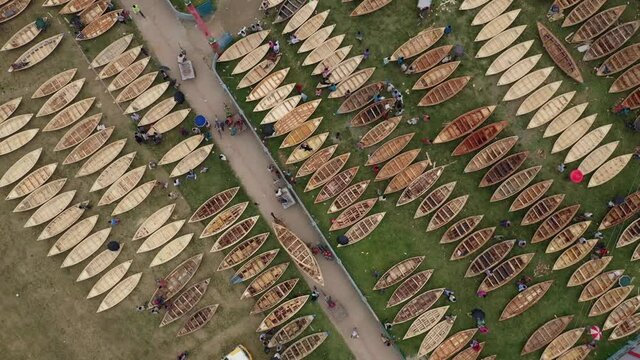 Aerial view of a few people working on repairing small wooden fishing boats in Ghior Central playground, Ghior, Dhaka, Bangladesh.