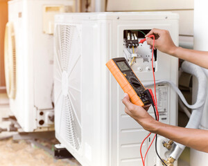 Air conditioner repairman using electricity meter to check air conditioner operation, maintenance concept
