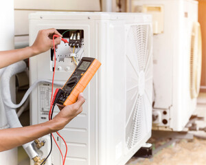 Air conditioner repairman using electricity meter to check air conditioner operation, maintenance...