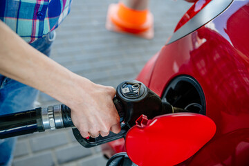 Woman's hand manually filling a car with gasoline, oil, fuel at a refueling station.