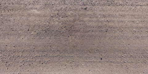 panorama of road from above on surface of gravel road with car tire tracks