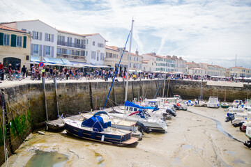 Fototapeta na wymiar View on the harbor of Saint-Martin-de-Ré at lowtide with boats and people walking on a sunny summerday
