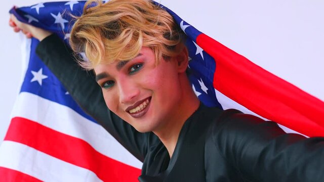 non binary portrait of asian man with luxurious blonde hair and gorgeous make-up wawing usa flag
