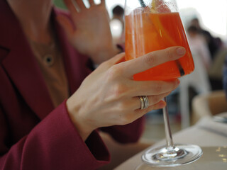 young beautiful woman eats in a restaurant, drinks a cocktail, coffee, jewelry on her hands, stylishly dressed