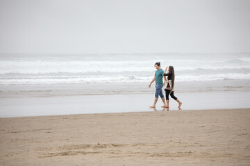 Young couple walking on empty beach next to ocean