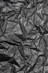 Black color background from sheet of crumpled carton, vertical view of abstract texture wrinkled cardboard material, pattern background.