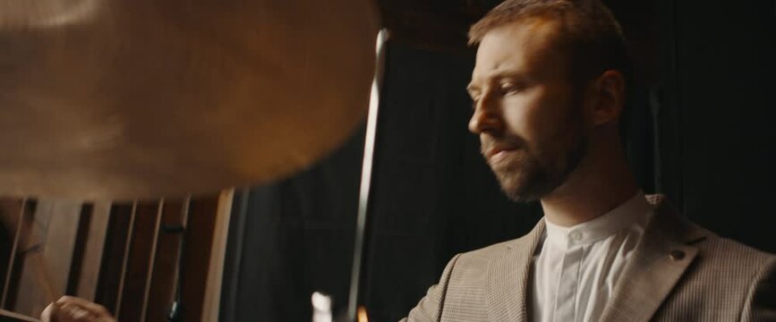 CU Caucasian male wearing suit playing drums during jass band rehearsal in recording studio. Shot with 2x anamorphic lens