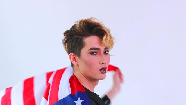 non binary portrait of asian man with luxurious blonde hair and gorgeous make-up wawing usa flag