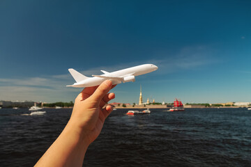 white plane in woman's hand on background of Peter and Paul Fortress in St. Petersburg, Russia