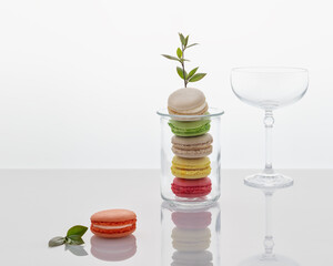 Spring romantic food still life with french dessert - macaroons with a blooming sprig and empty cocktail glass on a light background with a reflection and copy space. low carbs sweet pastries