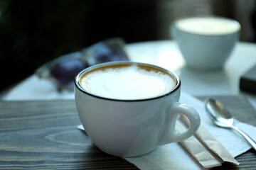 Cup of delicious coffee on wooden table outdoor in restaurant
