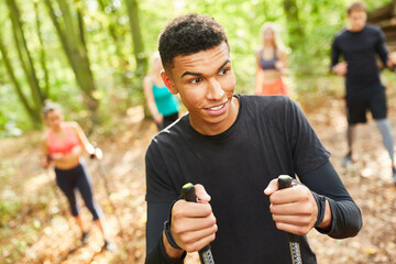 Junger Mann beim Nordic Walking mit Freunden