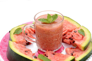 closeup sliced red ripe watermelon with juice and mint in the plate isolated on white background.