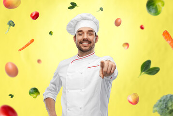 cooking, culinary and people concept - happy smiling male chef in toque pointing finger to camera...