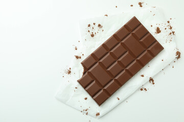Tasty chocolate bar on paper on white background