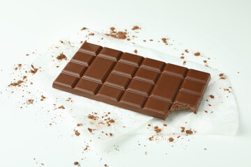 Tasty chocolate bar on paper on white background